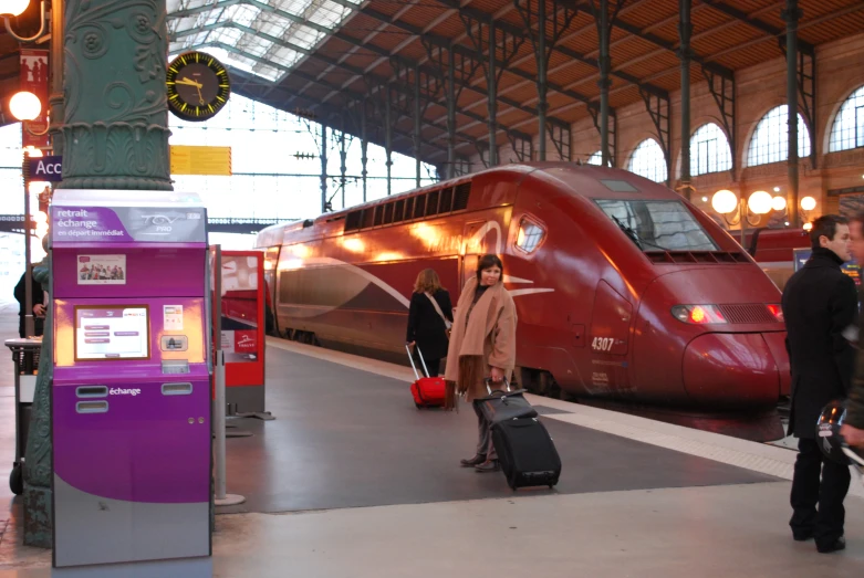 passengers board a train at an indoor train station