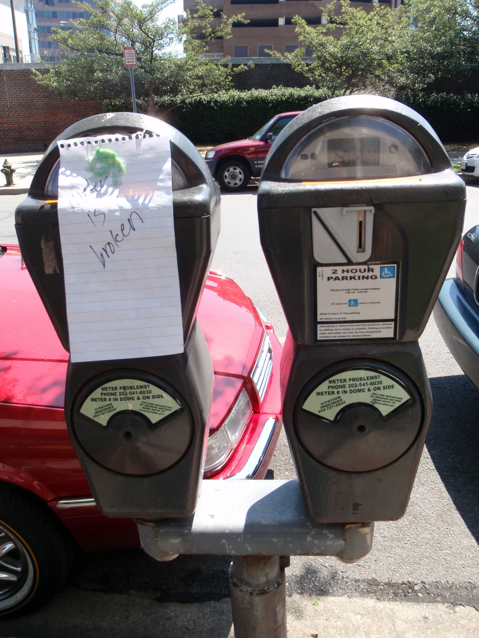 two parking meters with paper on top of each of them