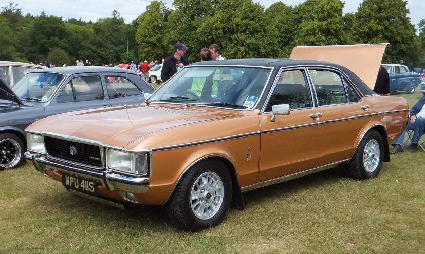 a car with an open hood parked in a field next to other cars