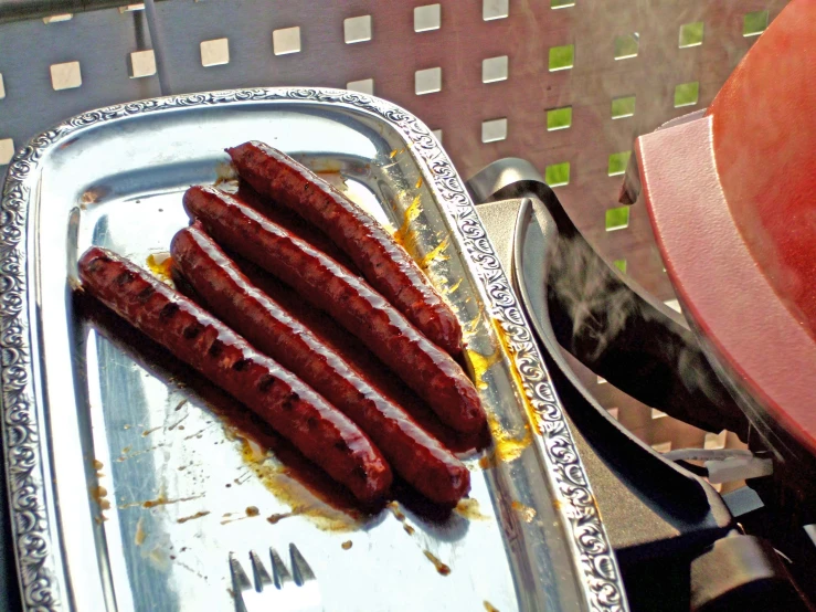  dogs in foil containers on a grill