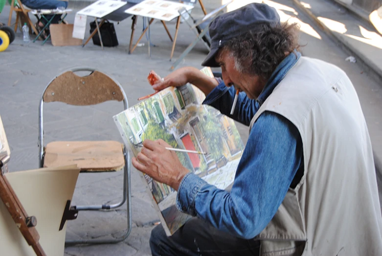 a man sits at a painting easel while looking at the picture