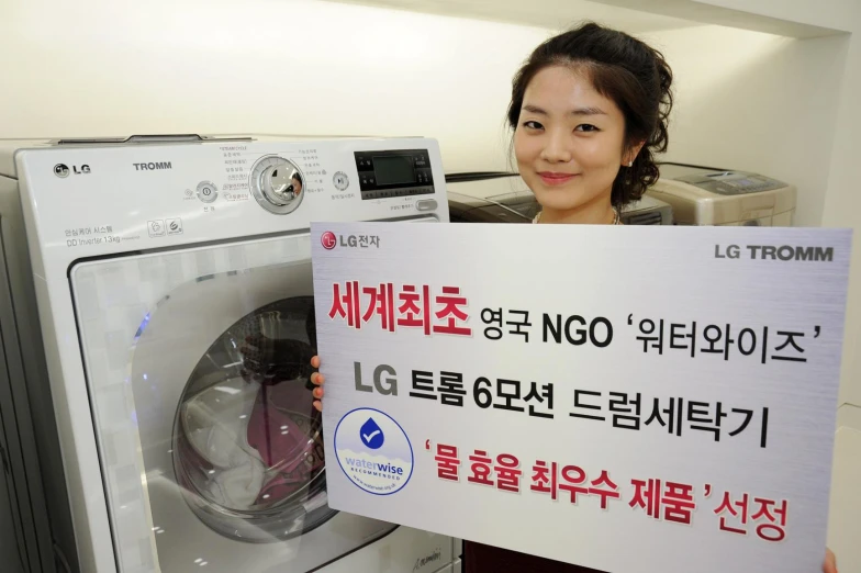 a woman holding up a sign in front of a washing machine