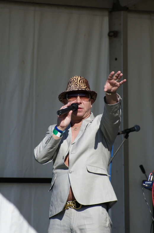 a man with hat and jacket is standing in front of microphone