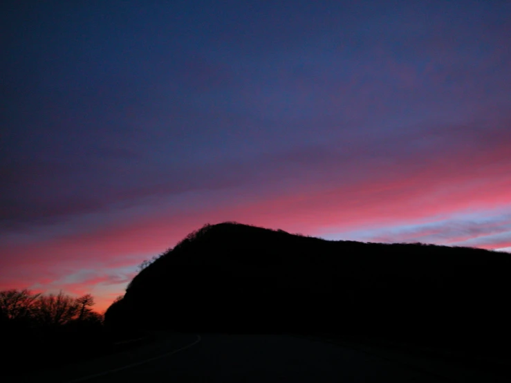 a colorful sky is shown with some trees and buildings