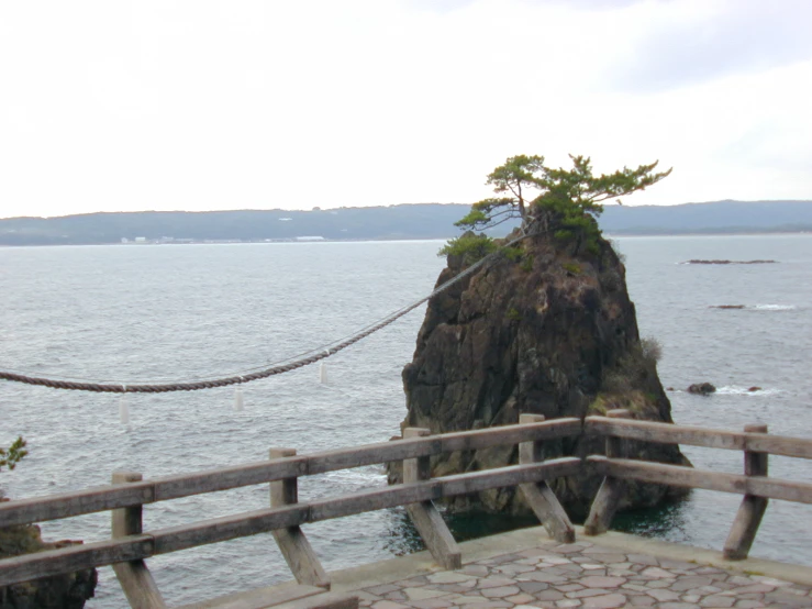 two people walk along a roped boardwalk on the ocean