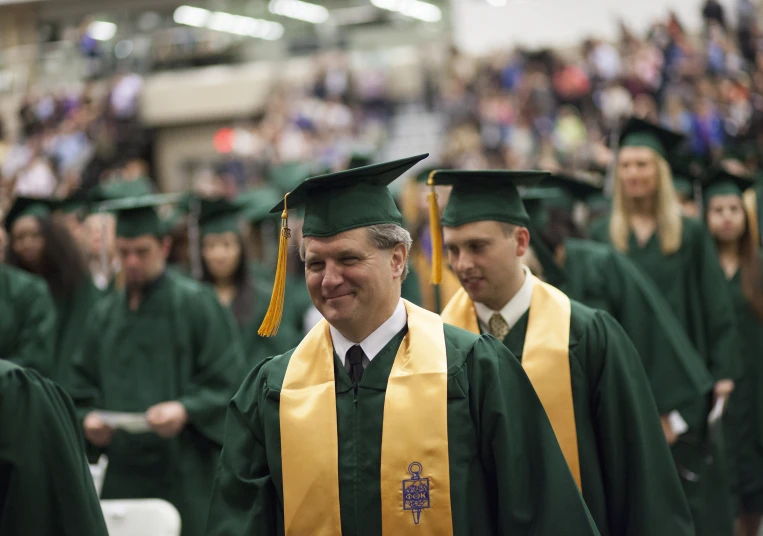 a group of people in green and yellow graduation hats