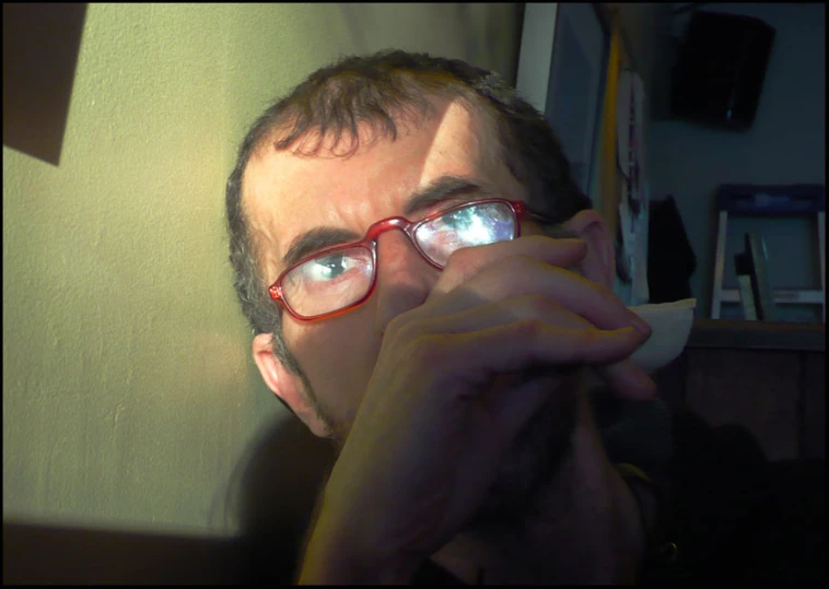 a man in glasses is holding soing to his face