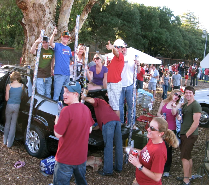 a crowd of people standing next to a parked car