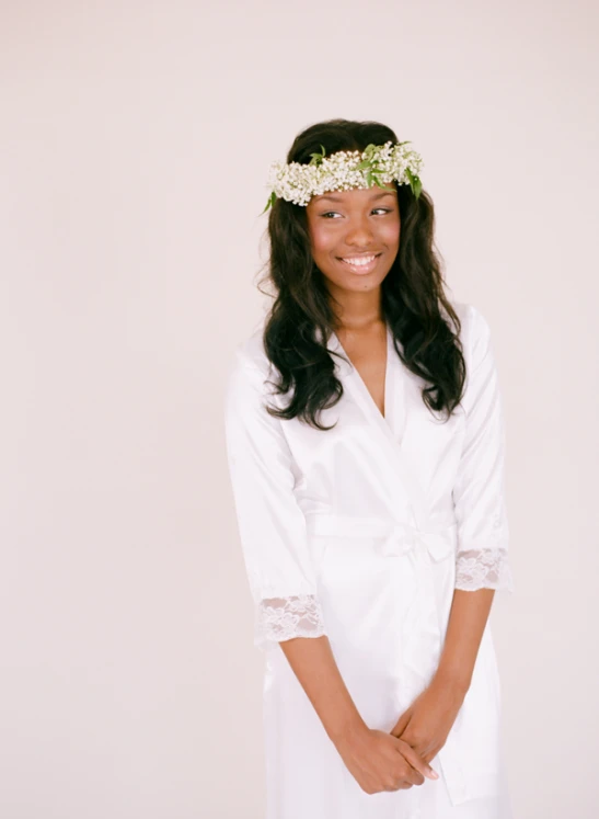 a woman in white is smiling with flowers in her hair