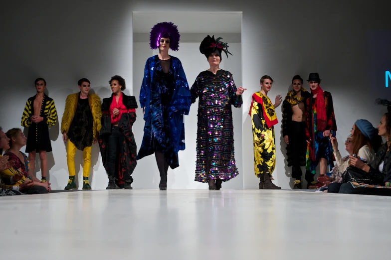 several fashion show with lots of colorful clothing on the runway