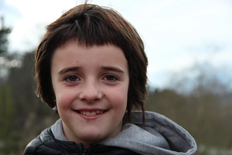 a little boy smiling in front of some trees