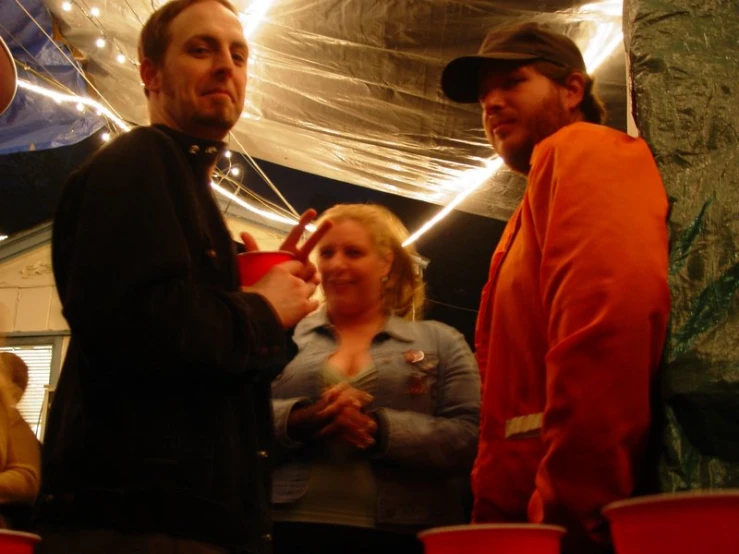 two men and two women standing next to each other with a tent in the background