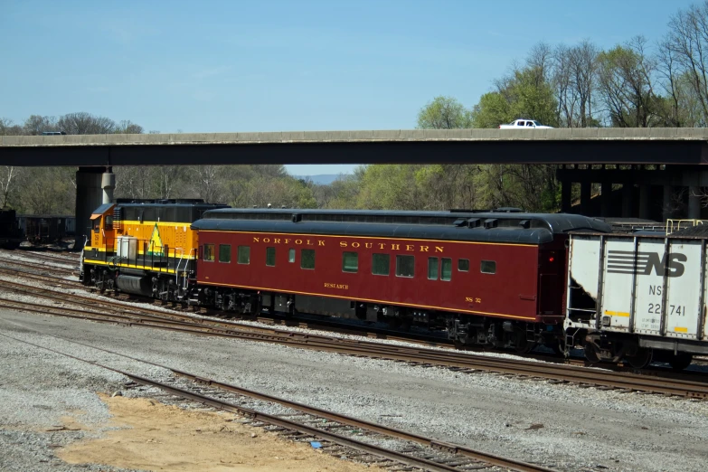 an old passenger train is parked on the tracks near a road