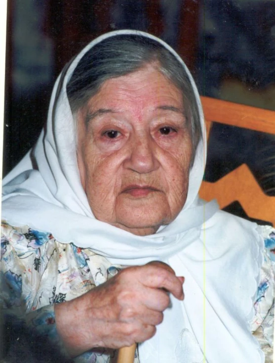 an older woman with a white headscarf looking into the camera