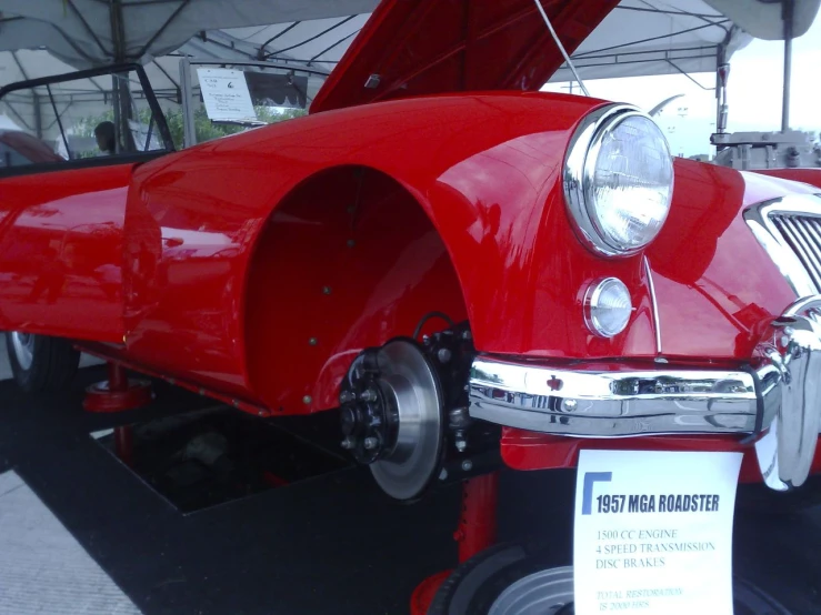 old time red automobile is on display under an umbrella