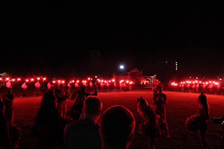 people in red dresses standing on a field with people lit up