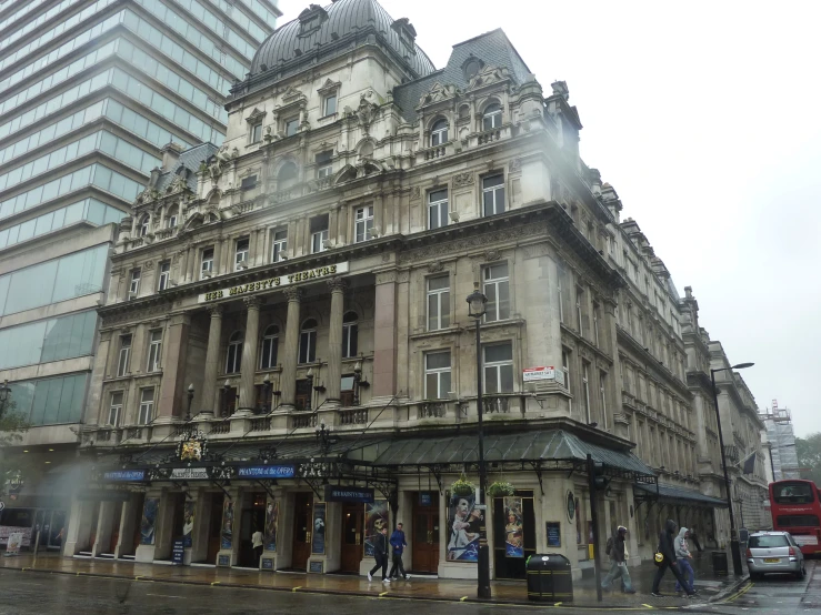 people walking by old buildings in the rain