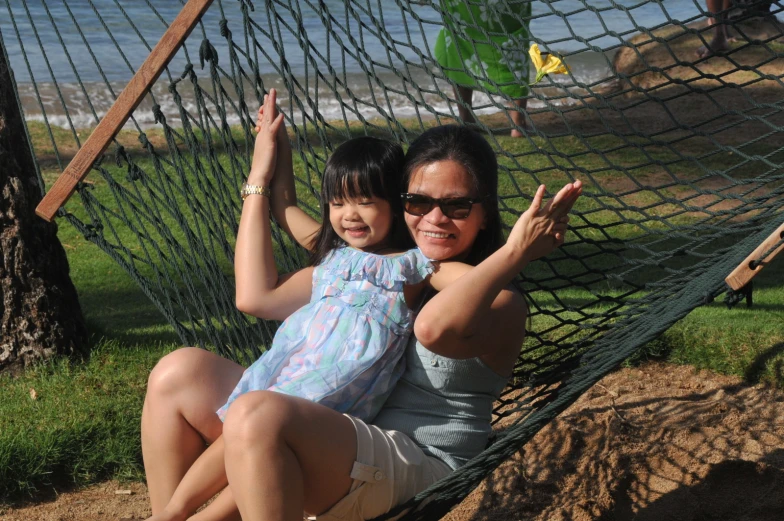 a woman and her daughter are lying in a hammock