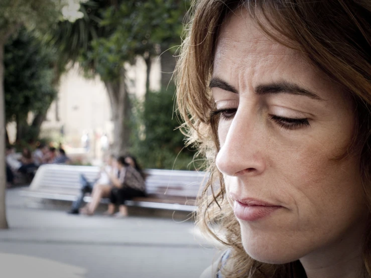 a woman looking down at her cell phone in a public place