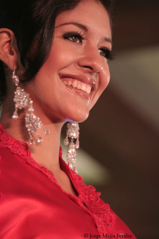 a smiling woman wearing jewelry and smiling for the camera