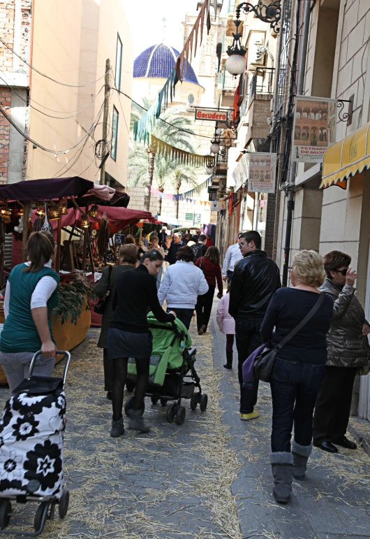 people on a city street, several in strollers