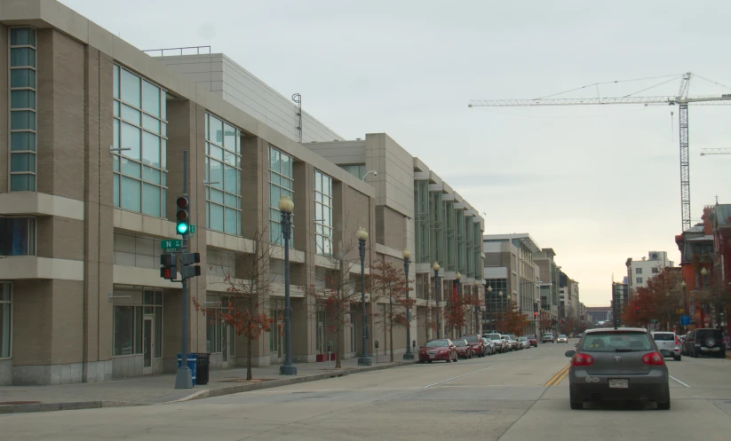 street scene with cars, building, traffic lights and construction cranes