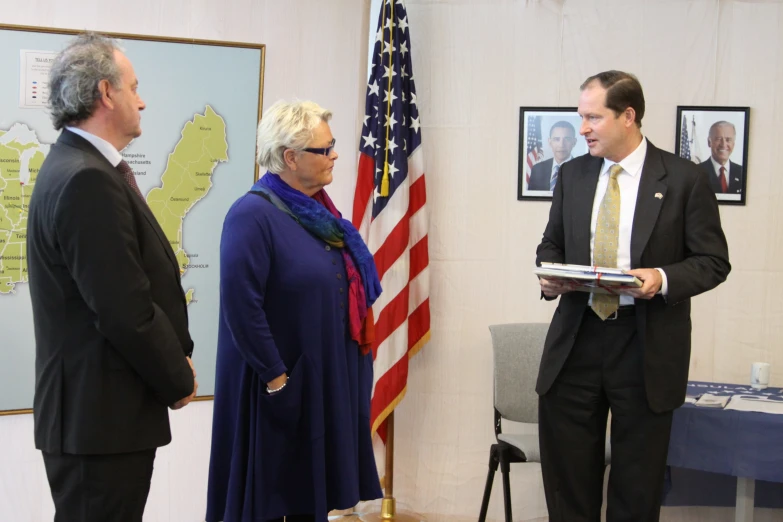 two gentlemen and a woman standing next to a flag