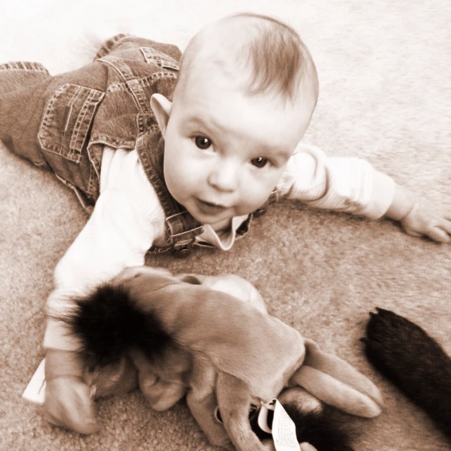 a baby is sitting on the ground with a stuffed animal