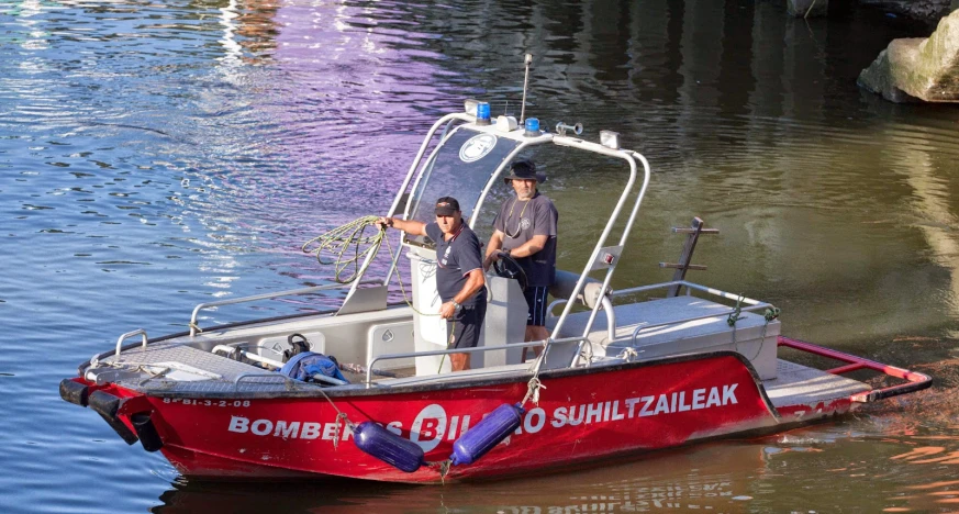 two police men are aboard of a boat on the water