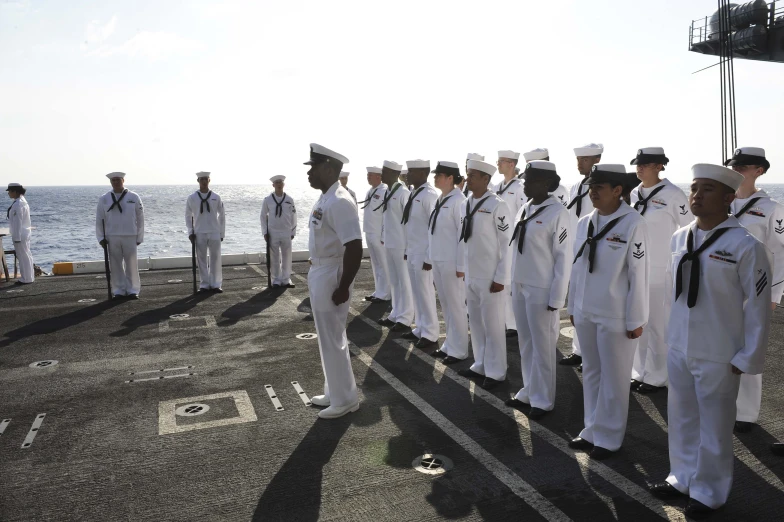 a line up of uniformed military men on a ship