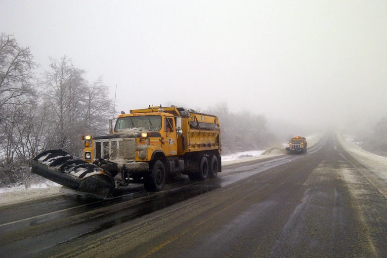 a snow plow driving down the snowy road