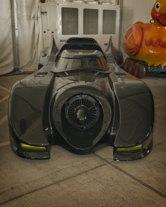 a grey race car is standing in front of some plastic orange blowouts