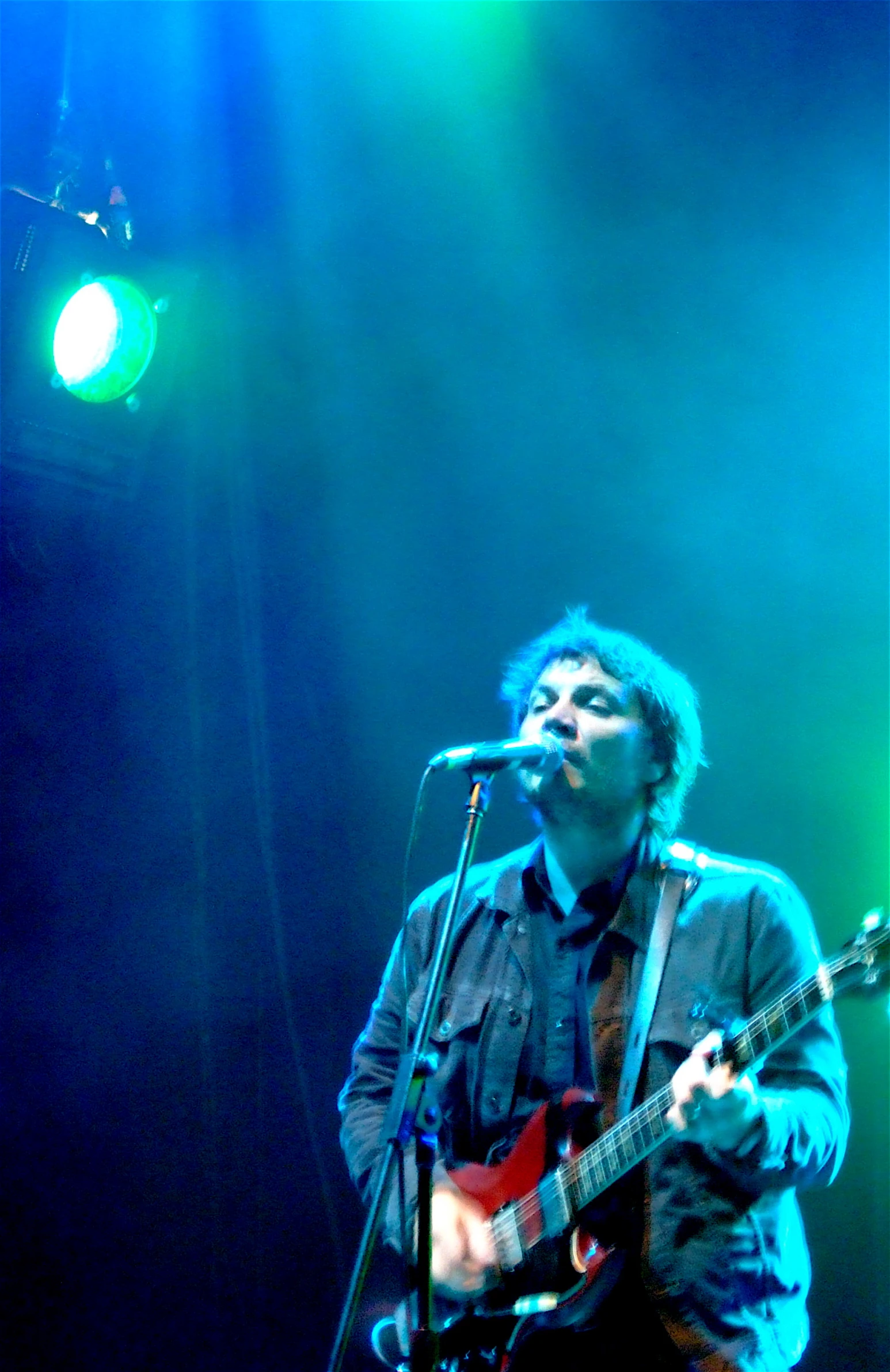 the man is singing into a microphone as he plays guitar