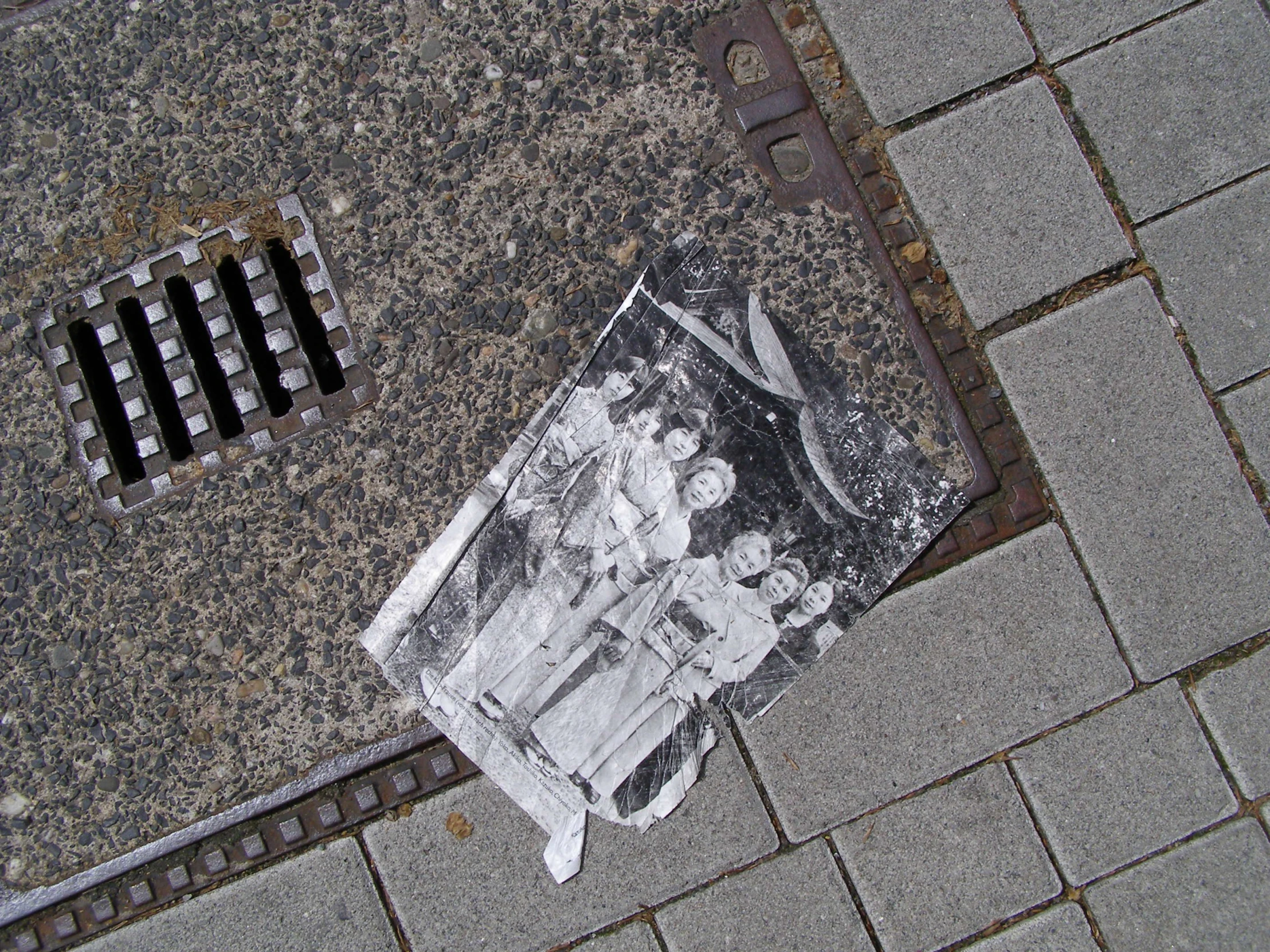 a newspaper lying on the ground with a metal grate