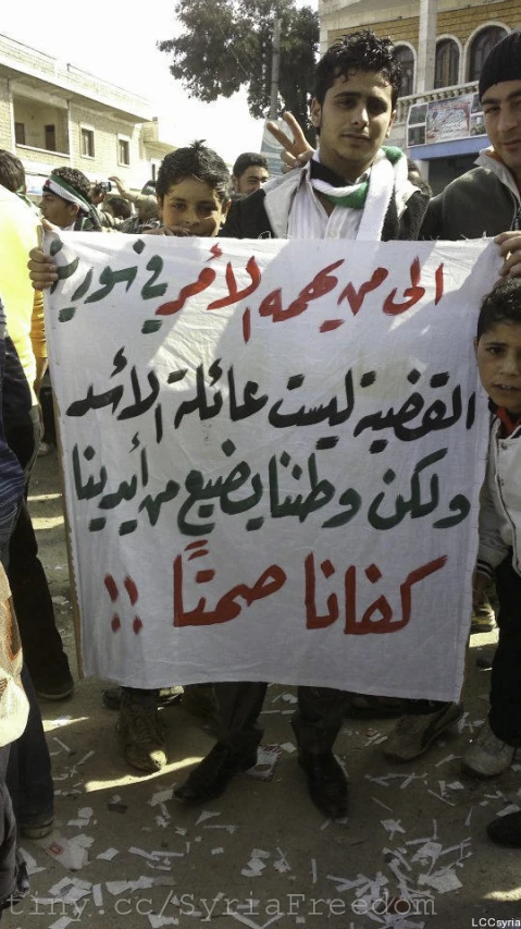 men and young children holding a protest sign in persian