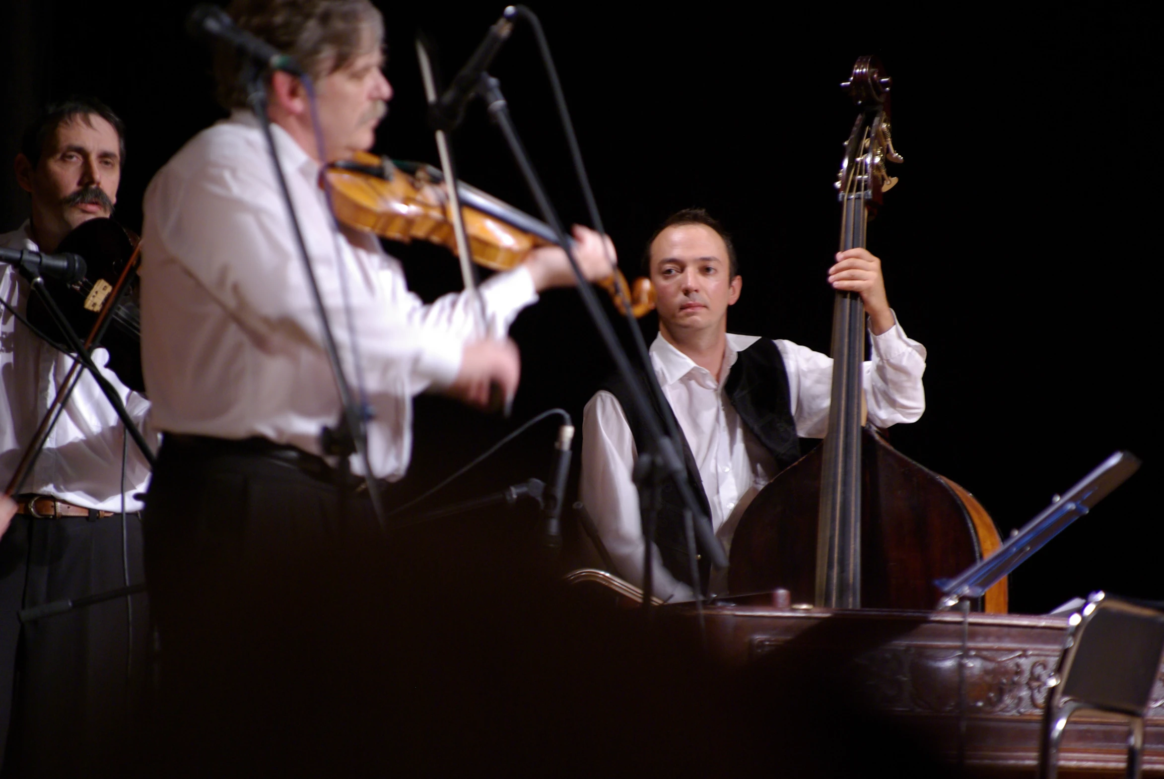 four male cellists are playing instruments on stage