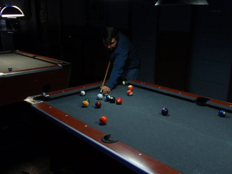 a man playing pool in a dark room