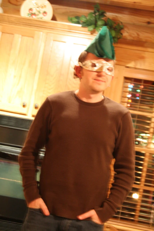 a man standing in front of a stove wearing a green elf's hat