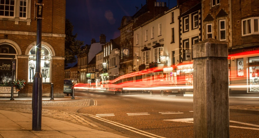 a city street with a red double decker bus speeding along