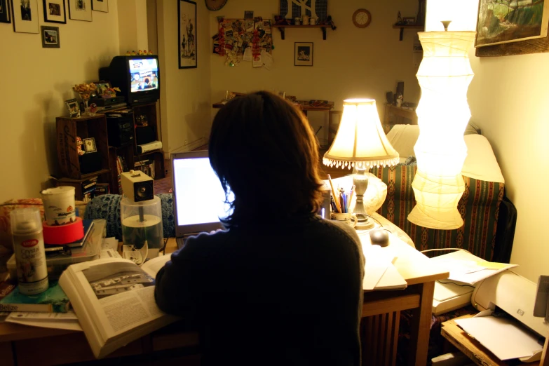 a woman using a computer in a room with a desk full of papers