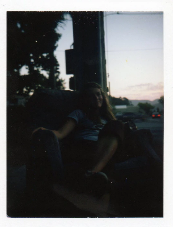 young woman sitting next to a skateboard in the middle of the night