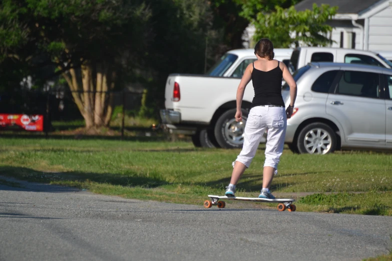 a woman rides on a skateboard while standing on the sidewalk