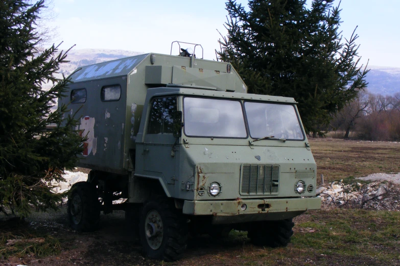 a large truck parked on the grass near some trees