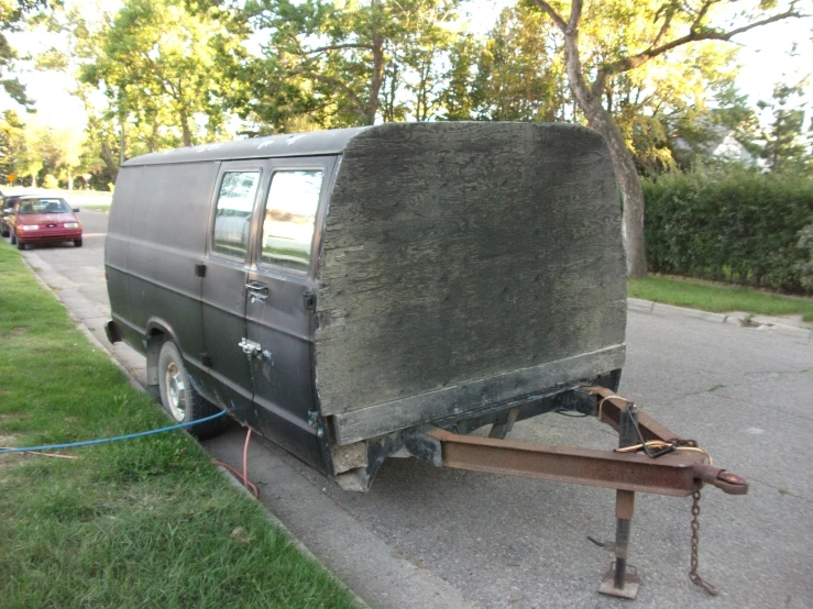 a black van with a wooden cart is on the street