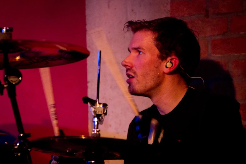 a man is staring at soing while playing drums