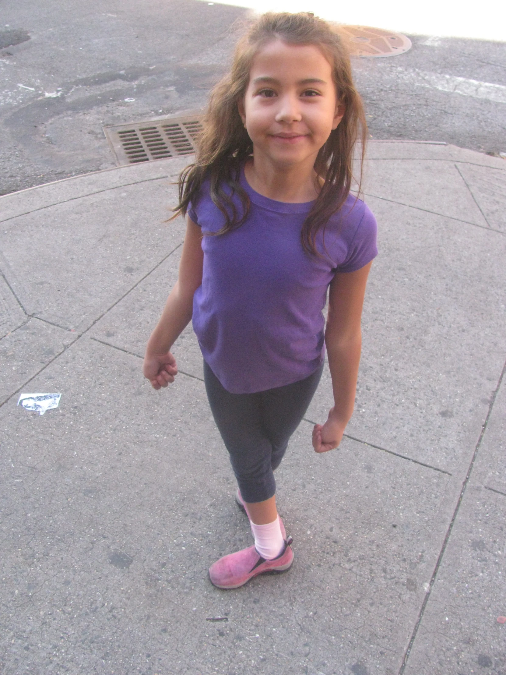 a little girl in purple shirt and leggings smiling