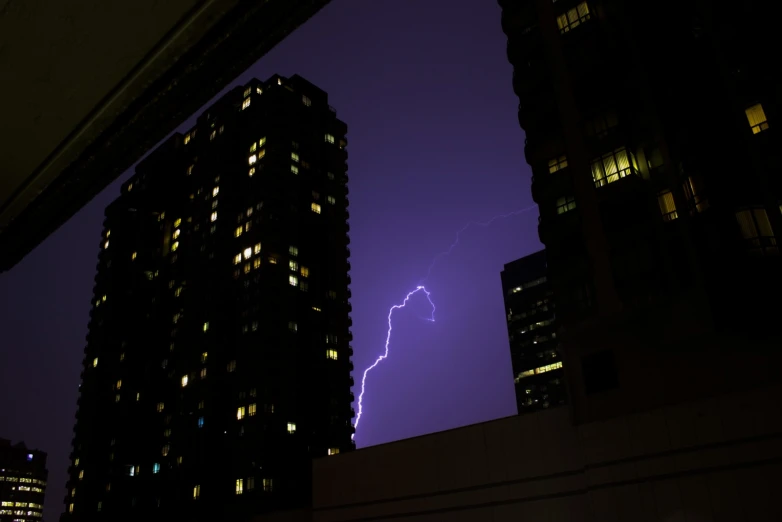 lightning striking behind a large building at night