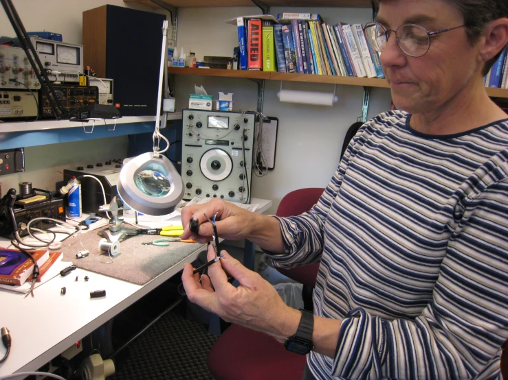 a woman in glasses is working on an item