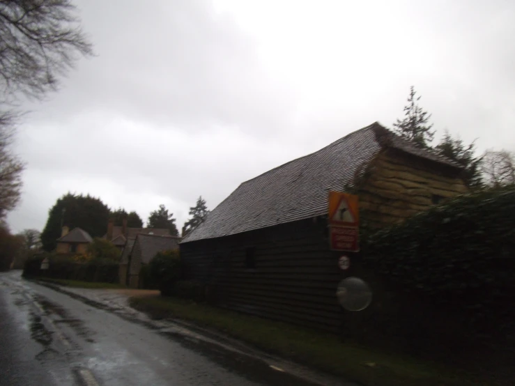 a wooden barn is seen against a cloudy sky