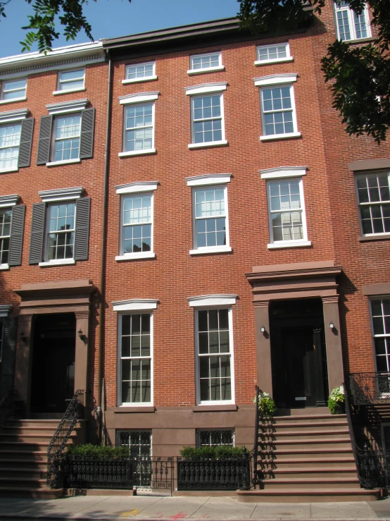 the outside of three brick houses on the sidewalk